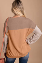 Woman wearing taupe and tan color block top with ribbed texture and long sleeves, perfect for a chic and comfortable fall look.