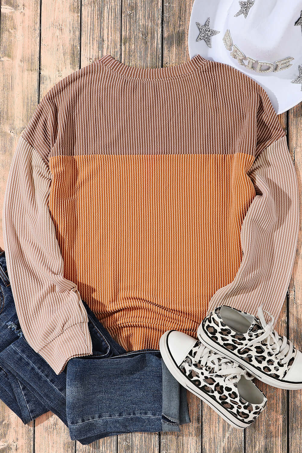 Taupe and tan color block long sleeve top with ribbed texture, paired with jeans, leopard print sneakers, and a star-studded hat.