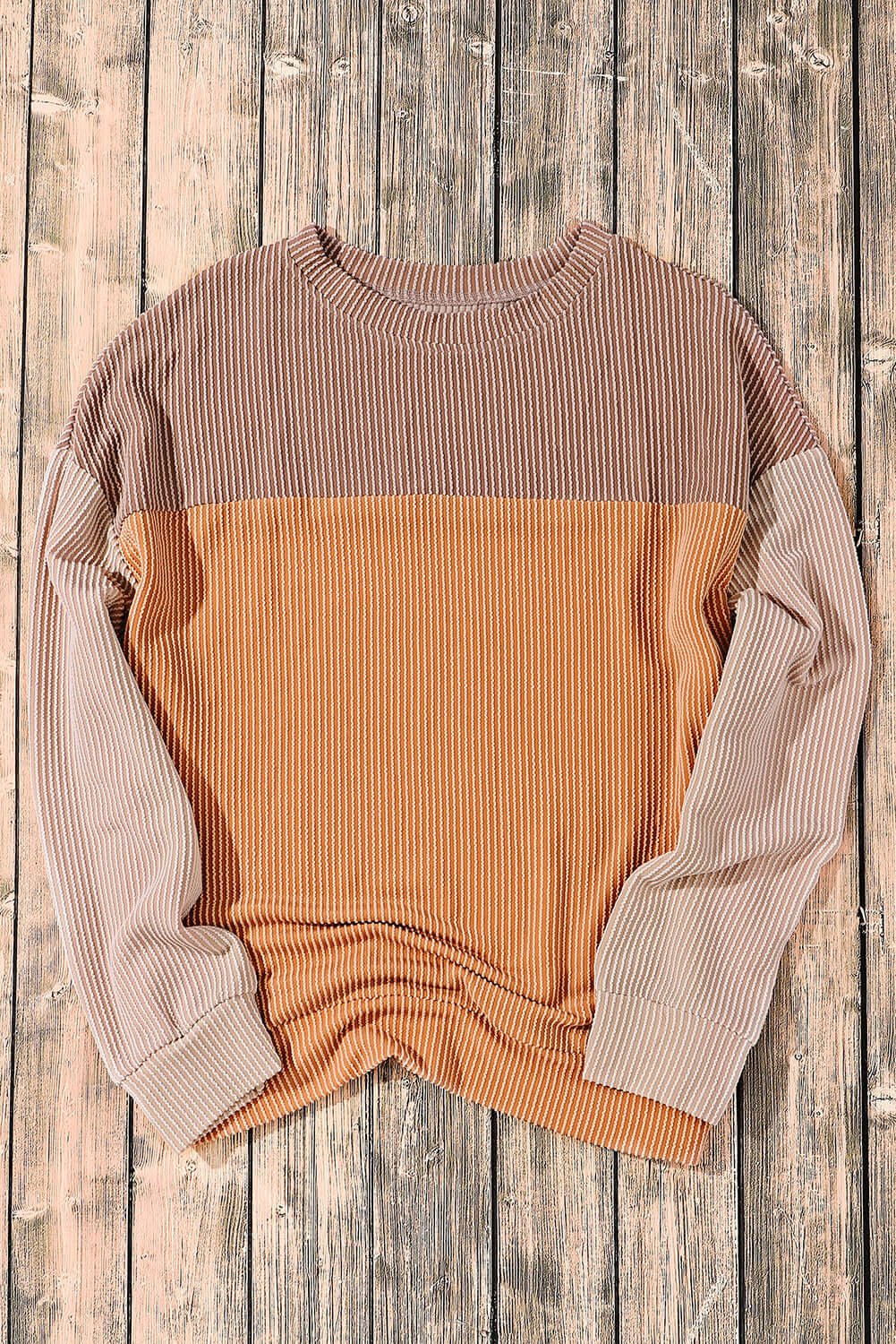 Taupe and tan color block ribbed top with long sleeves on wooden background, made from polyester, viscose, and elastane.