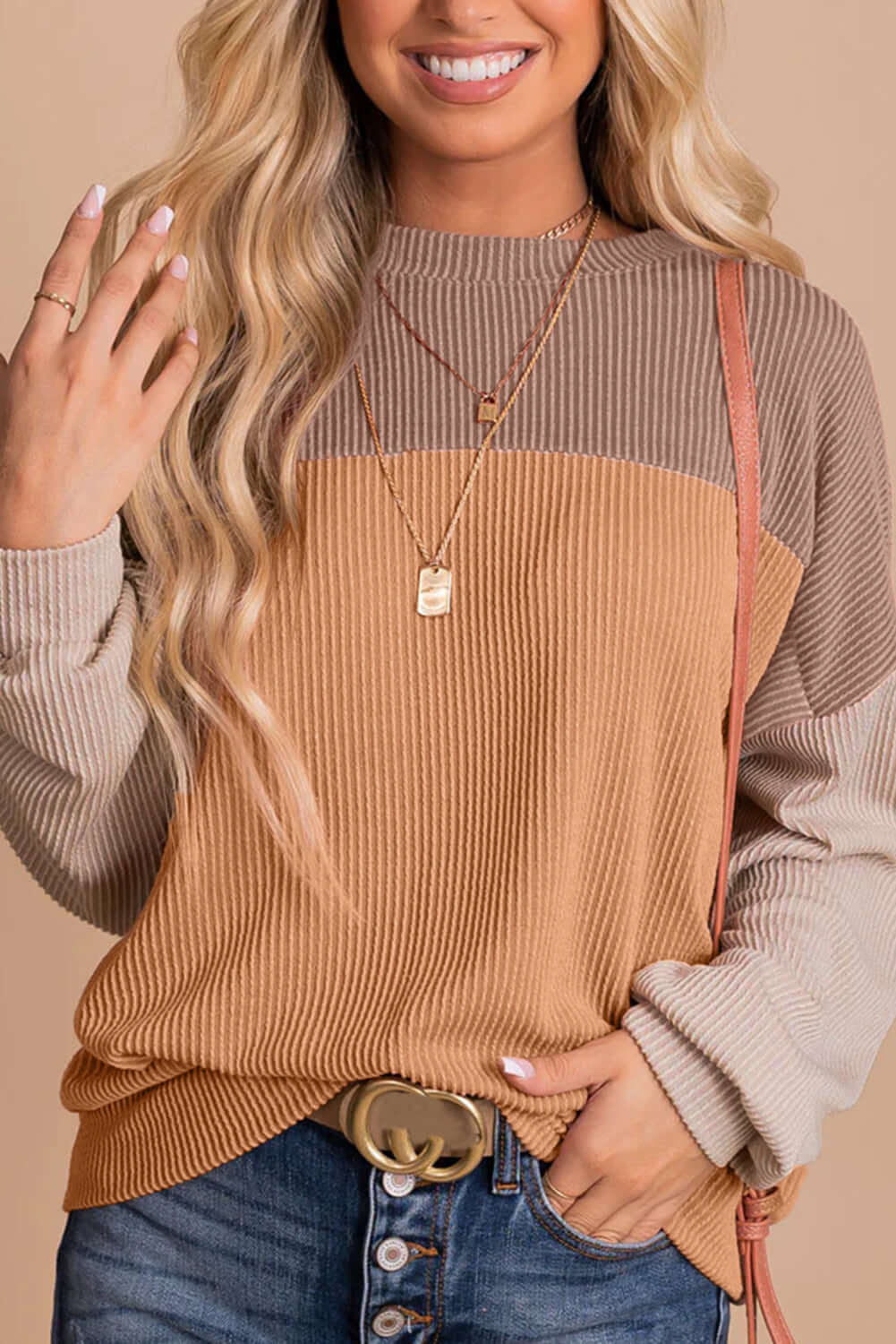 Woman wearing taupe and tan color block ribbed top with long sleeves and jeans