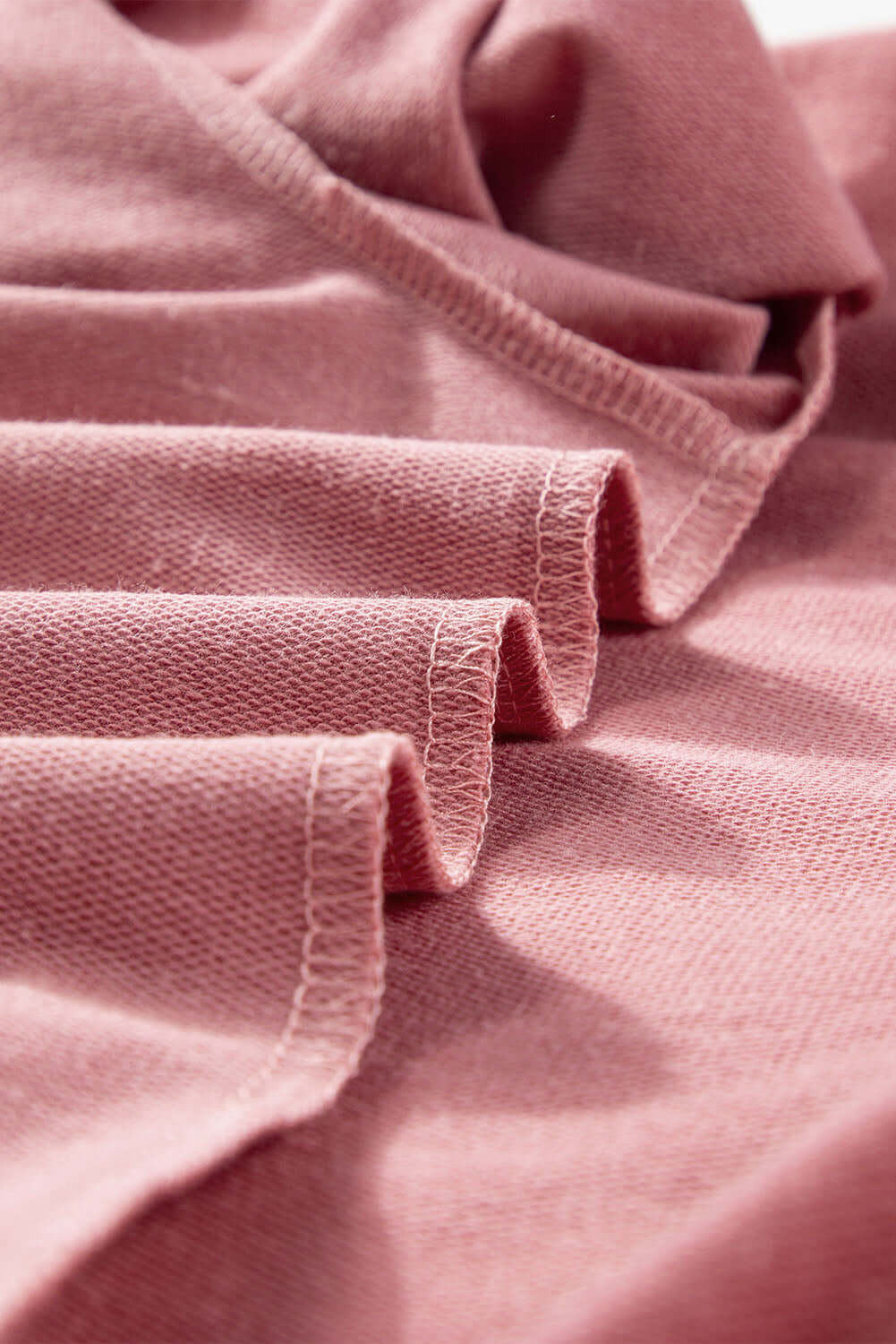 Close-up of soft pink fabric detail from the Rose by Any Other Name Top, highlighting elegant texture and finish.