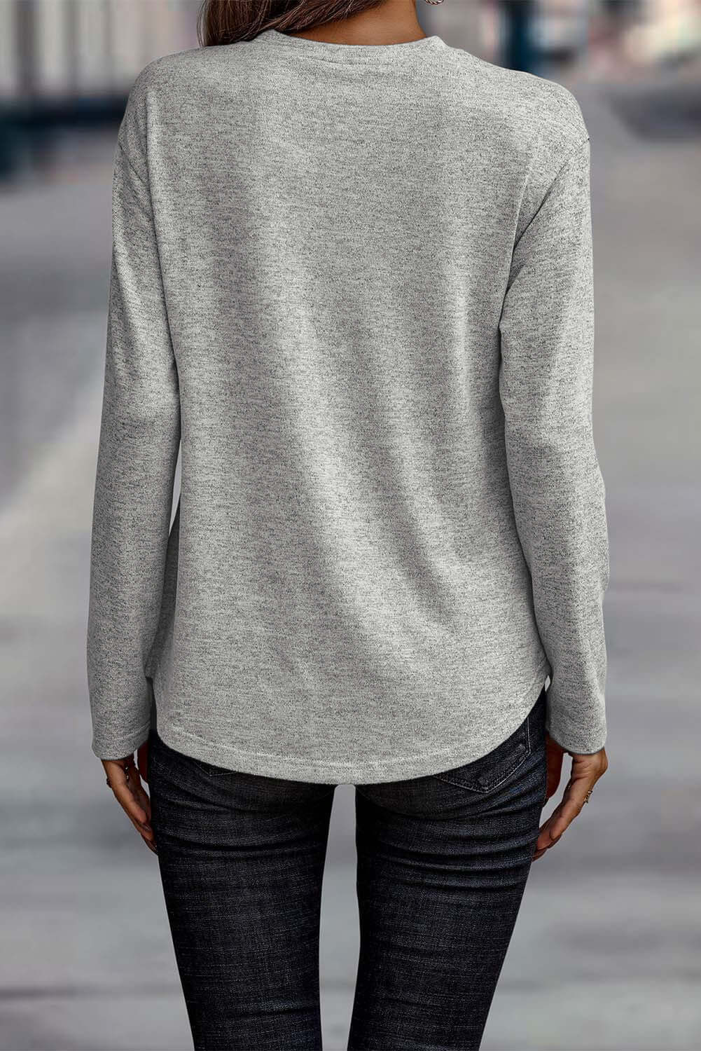 Woman wearing a misty gray long sleeve crew neck top, showcasing stylish side buttons and a regular fit from the back.