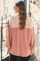 Woman wearing Boho Beauty Top by Vivian-Lu, showing back detail of floral contrast color block ribbed blouse in an outdoor setting.