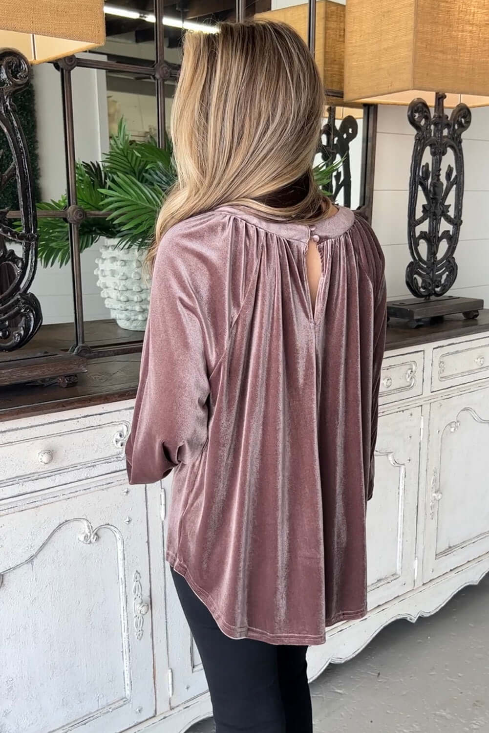 Woman wearing Lilac Luxe Top with pleated neckline and buttoned keyhole, showcasing elegant swing silhouette in plush velvet.