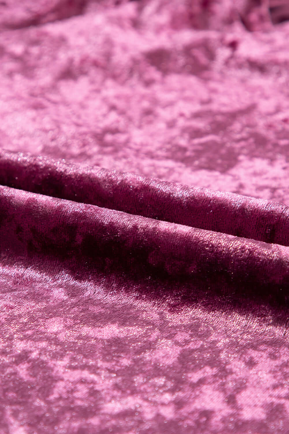 Close-up of rose pink crushed velvet fabric showcasing its rich texture and luxurious softness, ideal for stylish apparel.