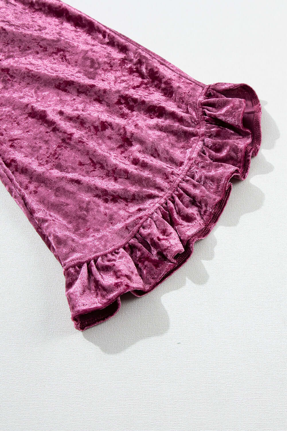 Close-up of velvet blouse sleeve in rose pink with ruffled pagoda design, showcasing luxurious, crushed velvet texture.