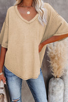 Woman wearing a relaxed cream knit top with V-neck and half sleeves, styled with jeans.