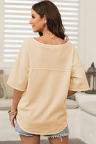 Back view of a woman wearing a relaxed cream top with dropped shoulders, showcasing a casual summer style.