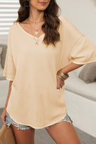 Woman wearing cream Carefree Mode Top, styled with denim shorts and layered accessories, perfect for summer outings.