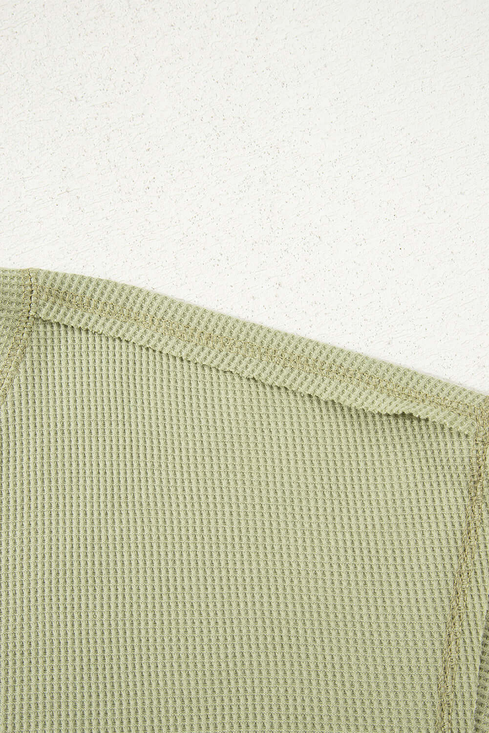Close-up of the texture and neckline of the Carefree Mode Top in sage green, showcasing its soft knit fabric.