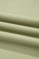 Close-up of textured sage green fabric, showcasing soft, breathable knit for casual summer wear.
