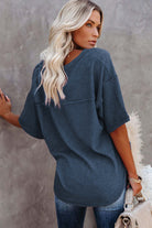 Woman in indigo Carefree Mode Top, stylishly relaxed with a modern V-neckline and textured knit design.