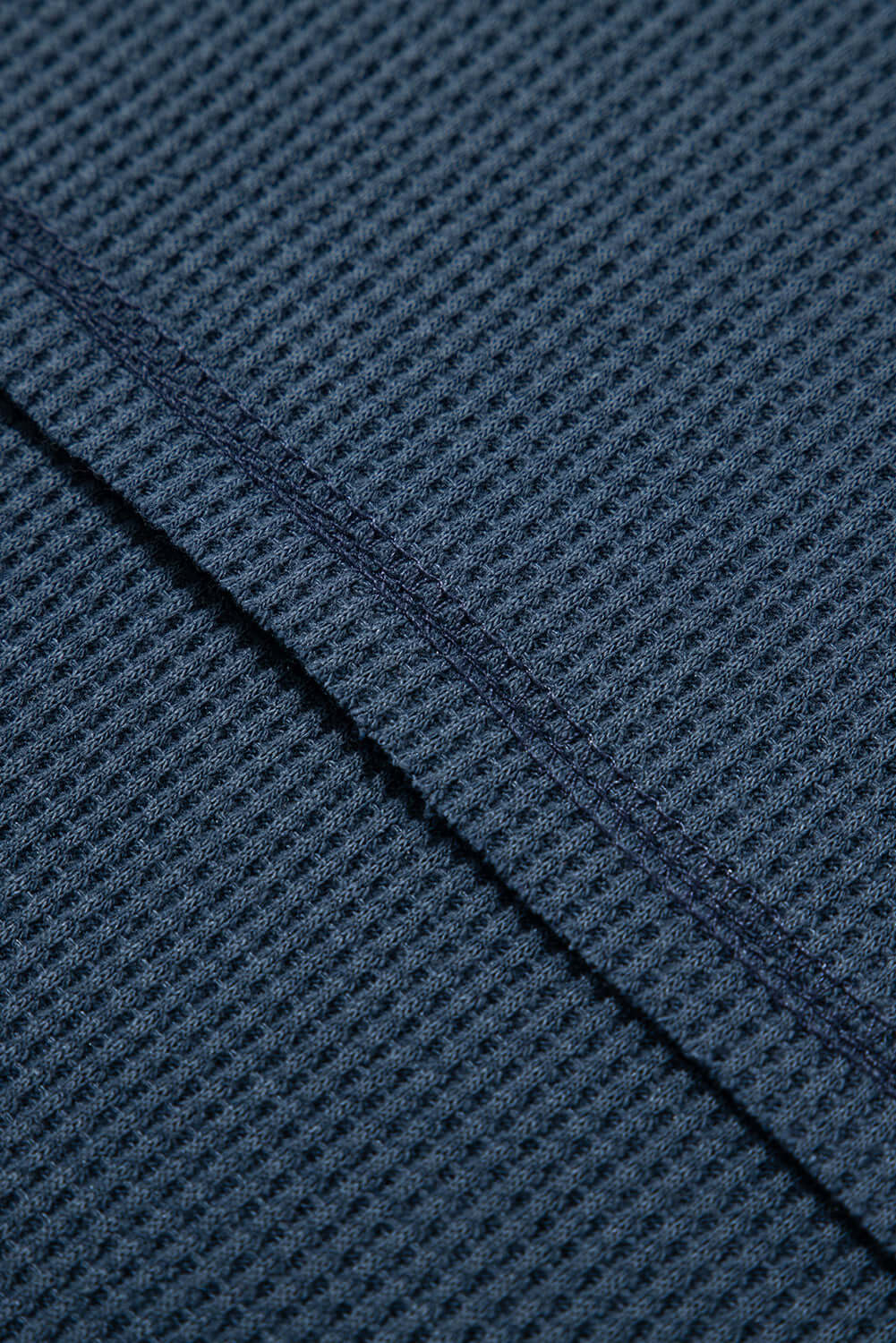 Close-up of the textured knit fabric in warm indigo blue showcasing exposed seam stitching, ideal for summer style.