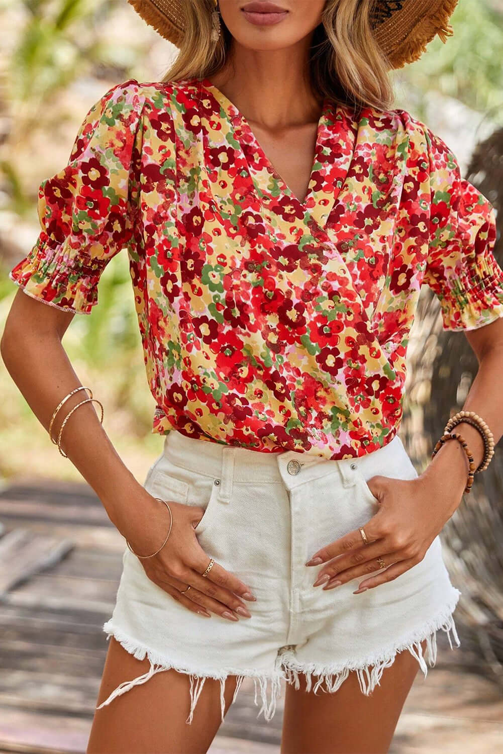 Stylish woman in Tropical Tango red floral blouse with bubble sleeves and white denim shorts, perfect for summer.