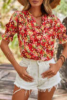 Stylish woman in Tropical Tango red floral blouse with bubble sleeves and white denim shorts, perfect for summer.