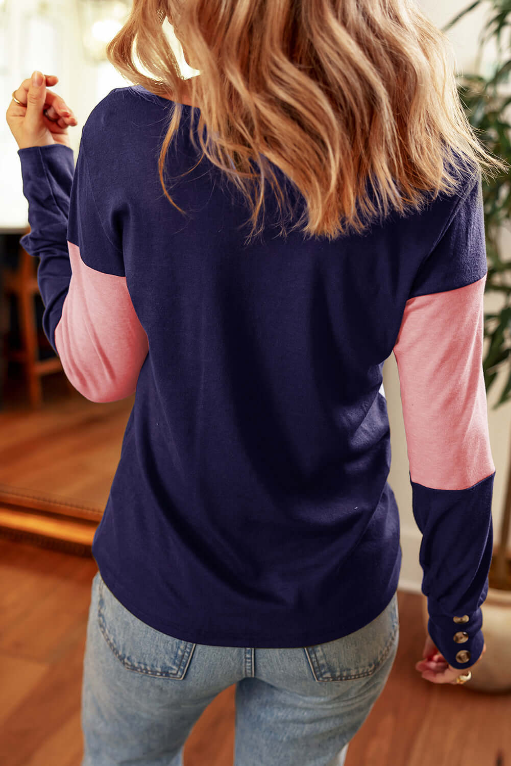 Woman wearing BETTER DAYS Top by Vivian-Lu, showcasing navy and pink color blocking and button detailing on the sleeves.