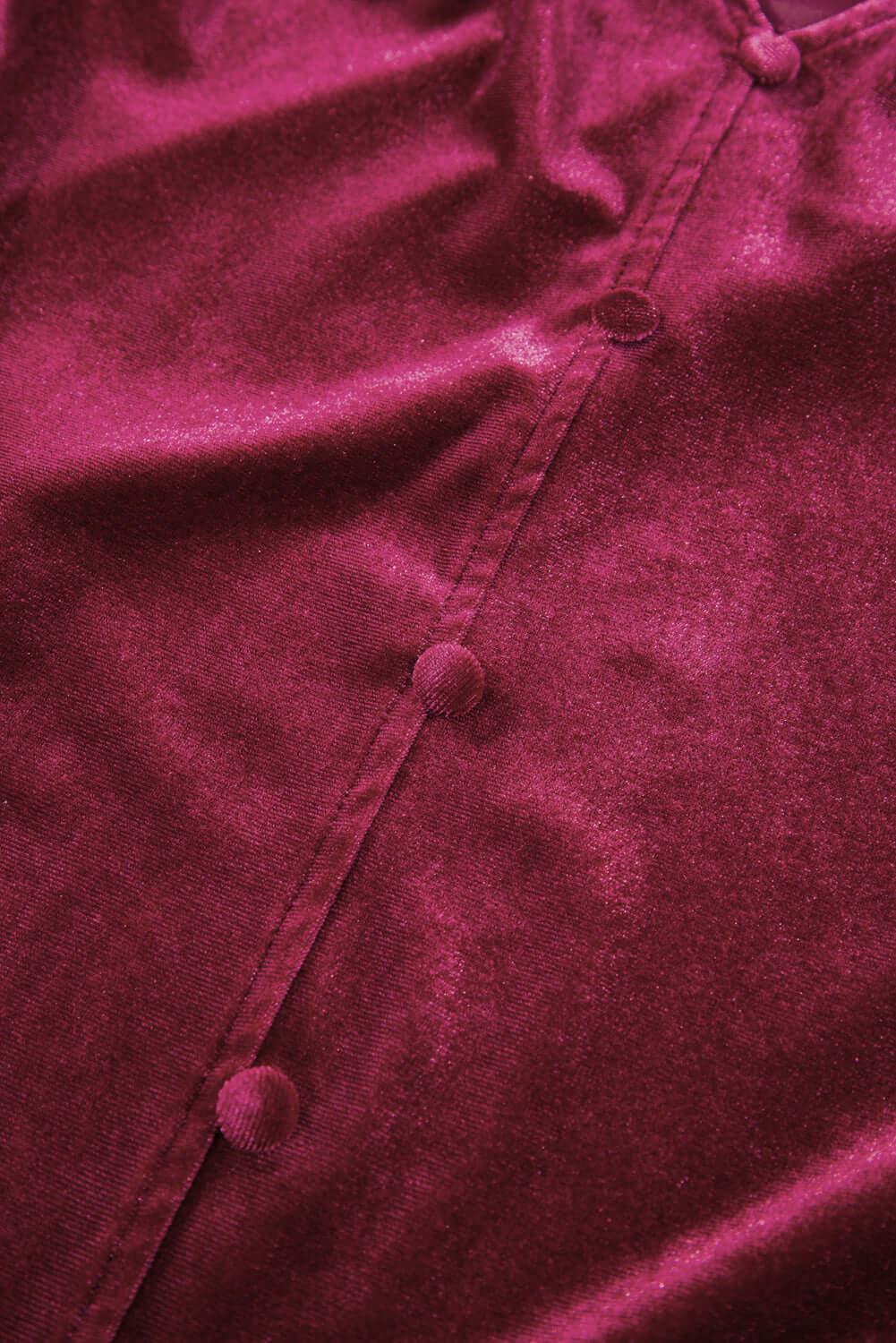 Close-up of soft burgundy velvet fabric featuring faux button accents, showcasing the luxurious texture of the SEQUIN SIREN top.