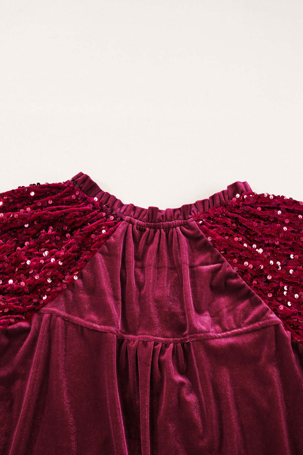 Close-up of SEQUIN SIREN top showcasing velvet fabric and dazzling sequined sleeves in rich burgundy color.