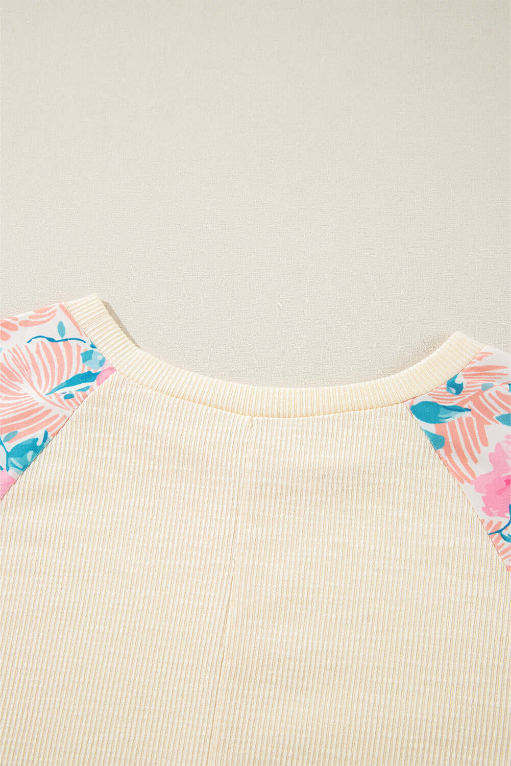 Lightweight vanilla ribbed top with floral patchwork sleeves, featuring an elegant crew neck and banded bottom.