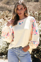 Woman modeling a lightweight vanilla top with floral patchwork sleeves, showcasing a trendy and sophisticated style.