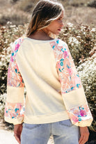 Lightweight vanilla top with floral balloon sleeves, exuding sophistication and style in a trendy outdoor setting.