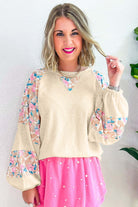 Lightweight vanilla ribbed top with floral patchwork, balloon sleeves, and classic crew neck, styled with a pink skirt.