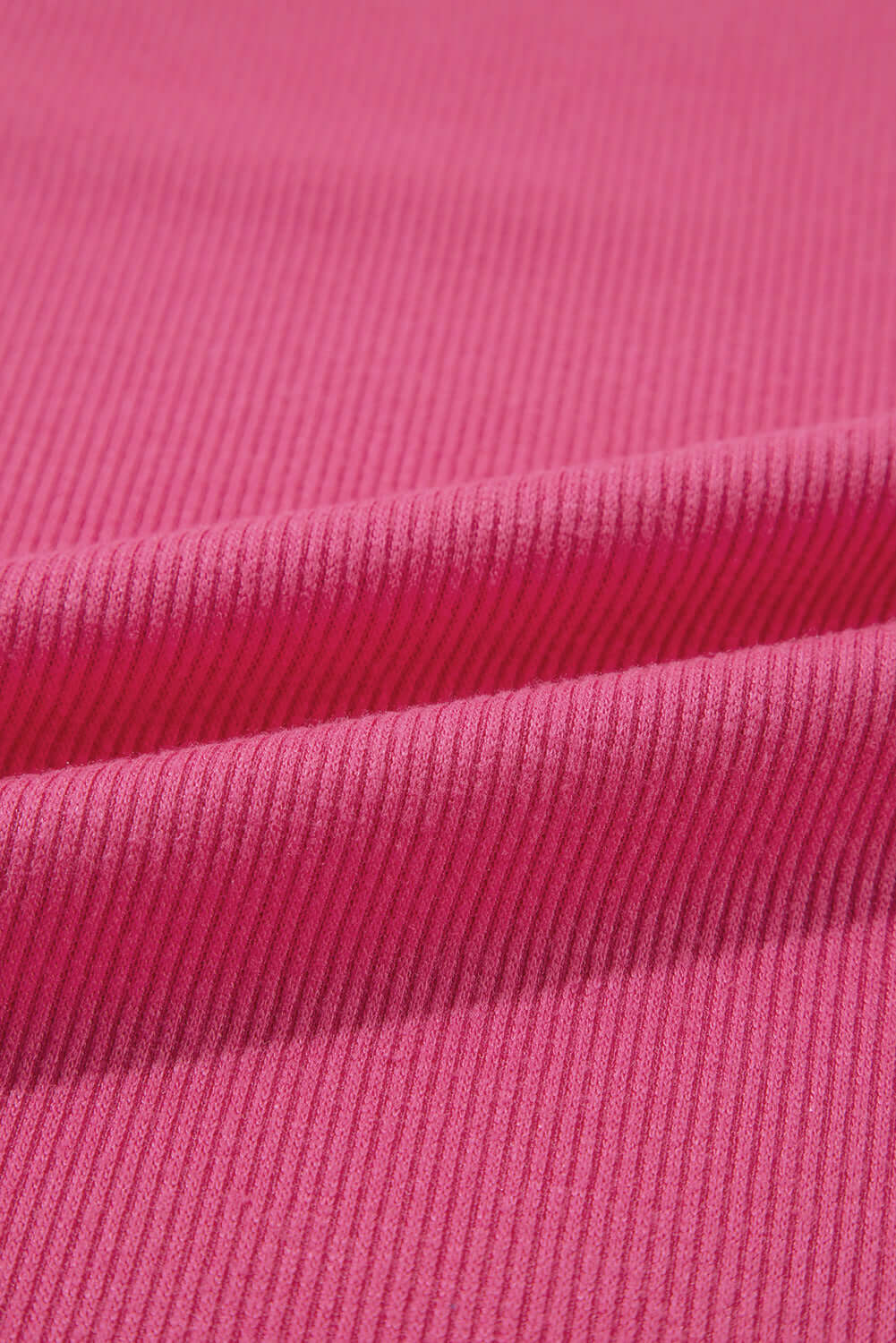 Close-up of pink ribbed knit fabric showcasing its texture and softness, ideal for stylish clothing like tops.