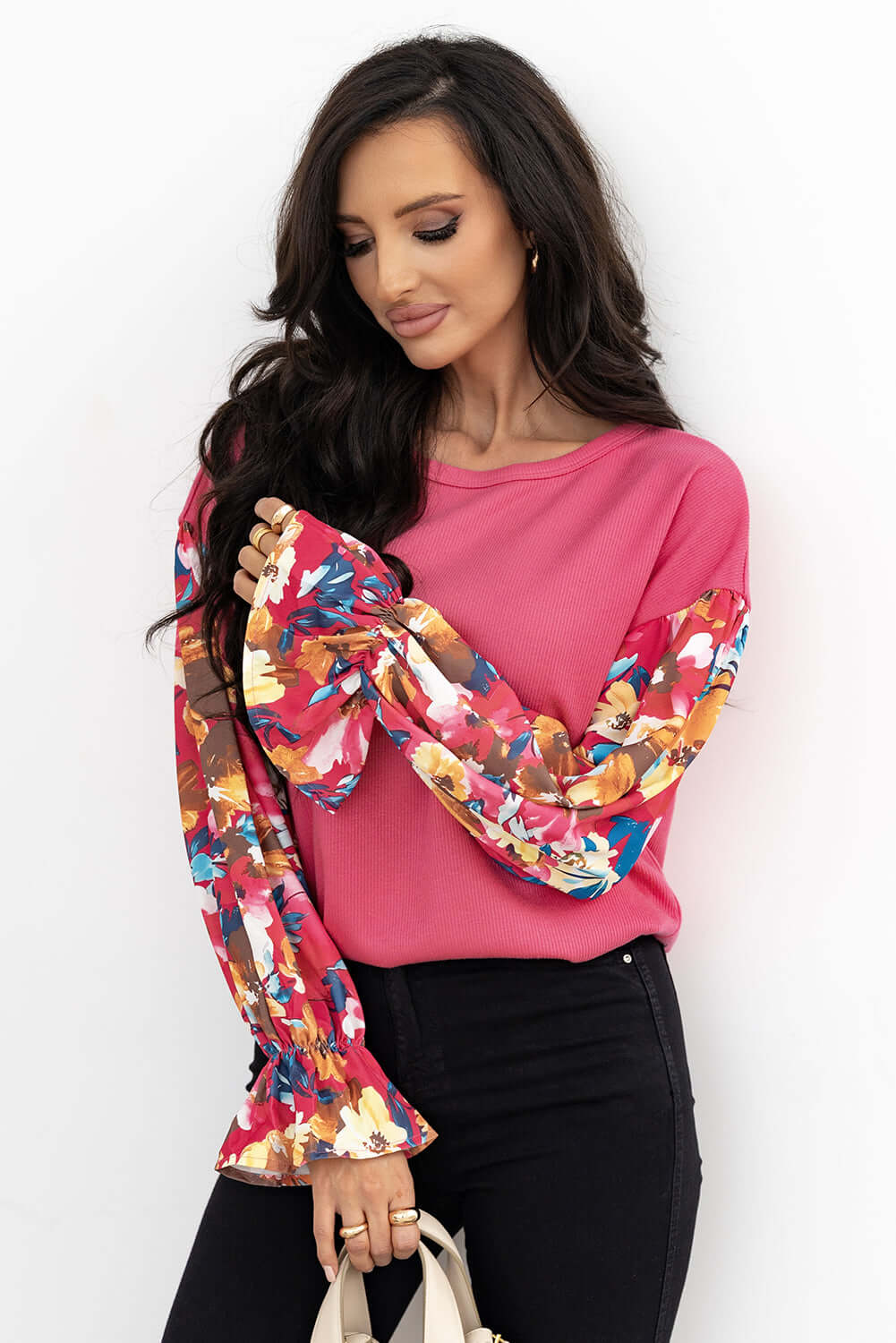 Woman in pink Petal Perfection top with colorful ruffled sleeves, styled with black jeans and a handbag.