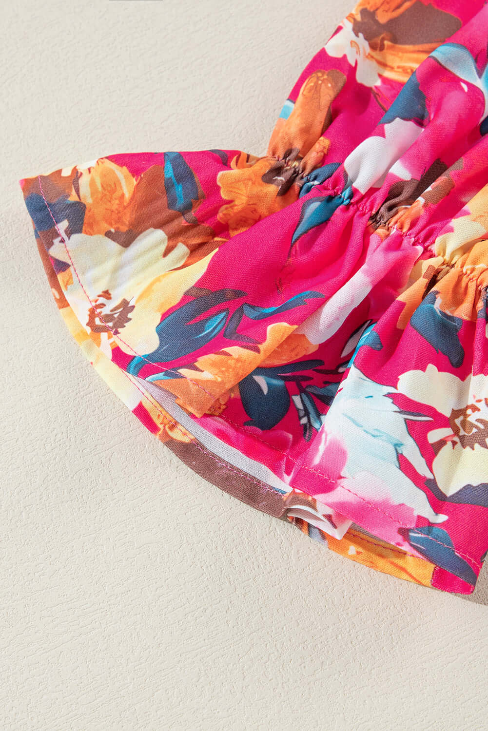 Colorful floral patchwork design of Petal Perfection top with ruffled sleeves on a neutral background.