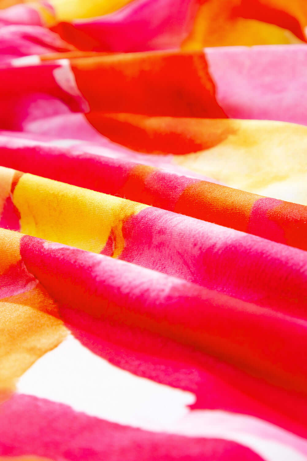 Close-up of vibrant brush stroke fabric in pink, yellow, and orange hues for SUNKISSED BABE TOP.