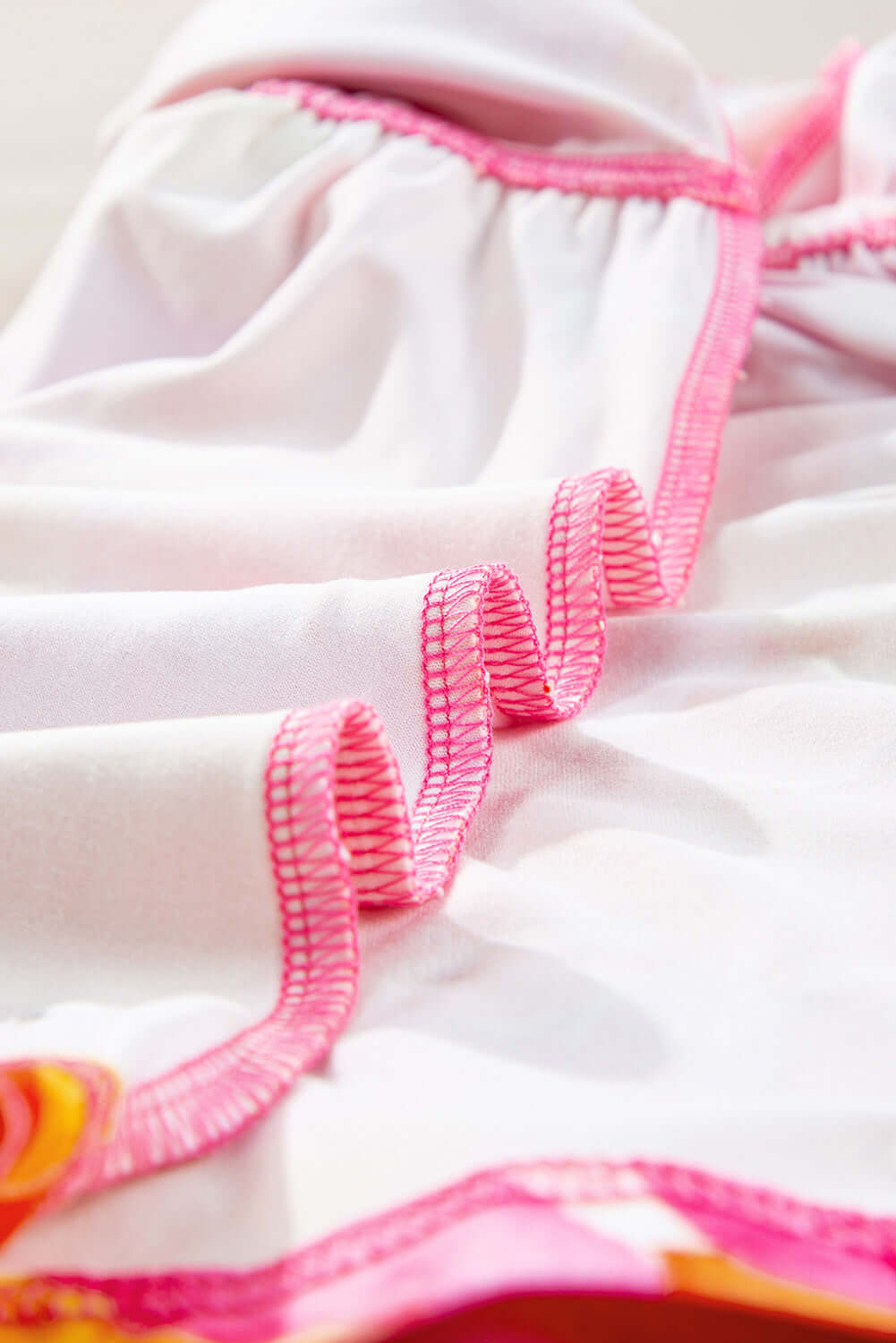Close-up of SUNKISSED BABE TOP with pink trim, showcasing soft fabric and unique brush stroke design.