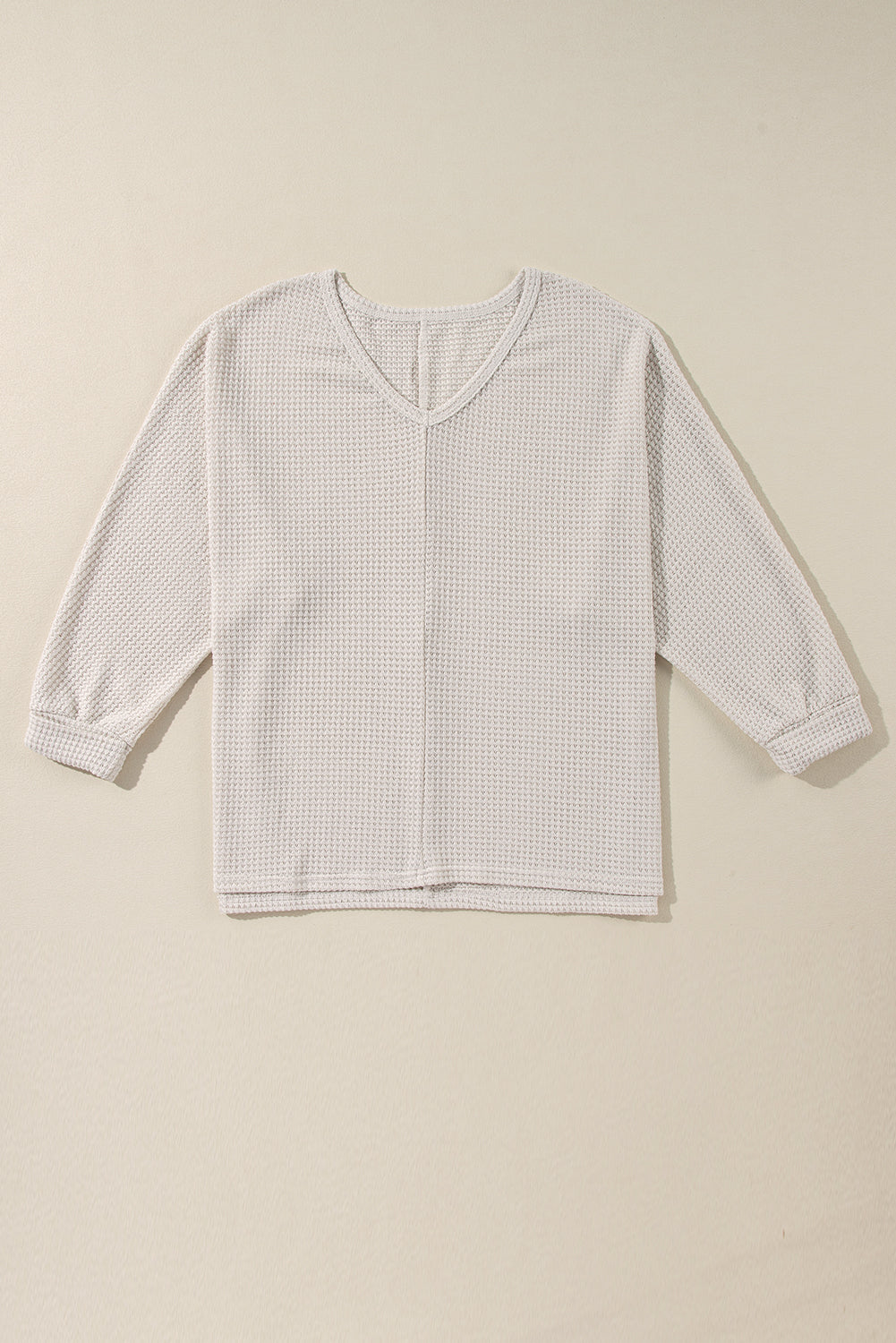 Vanilla waffle knit top with V-neckline and loose fit on beige background