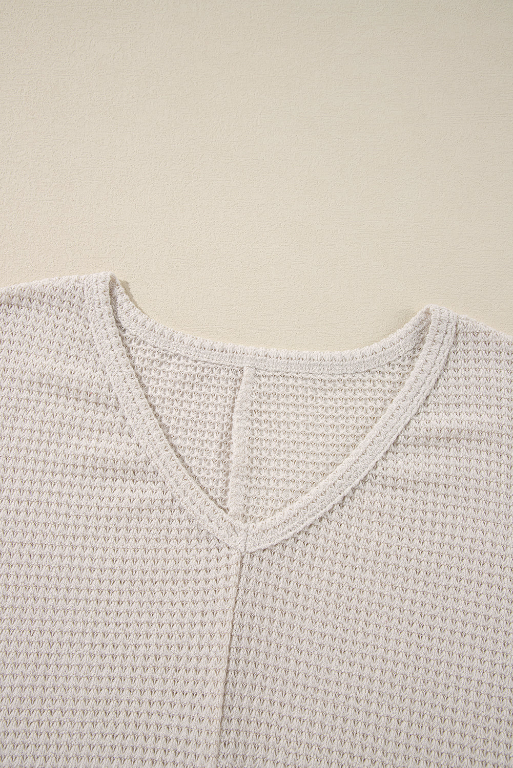 Luxurious waffle knit top in vanilla with V-neckline and loose fit design.