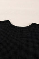 Back view of the black Finally Made It top showcasing its textured waffle knit design and elegant neckline.