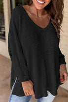 Woman smiling in a black waffle knit Finally Made It top with V-neckline and loose fit, perfect for casual styling.