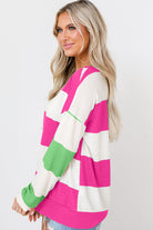 Woman wearing fuchsia and green color block striped top with long sleeves, showcasing a relaxed drop shoulder design.