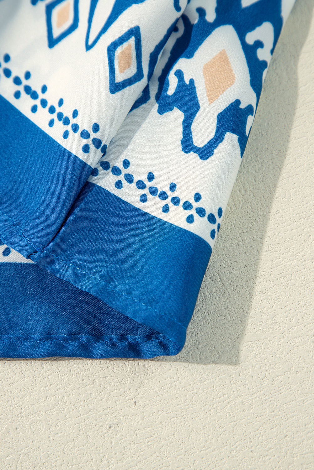 Detail of Follow The Music top showcasing cobalt blue fabric with white and peach accents.