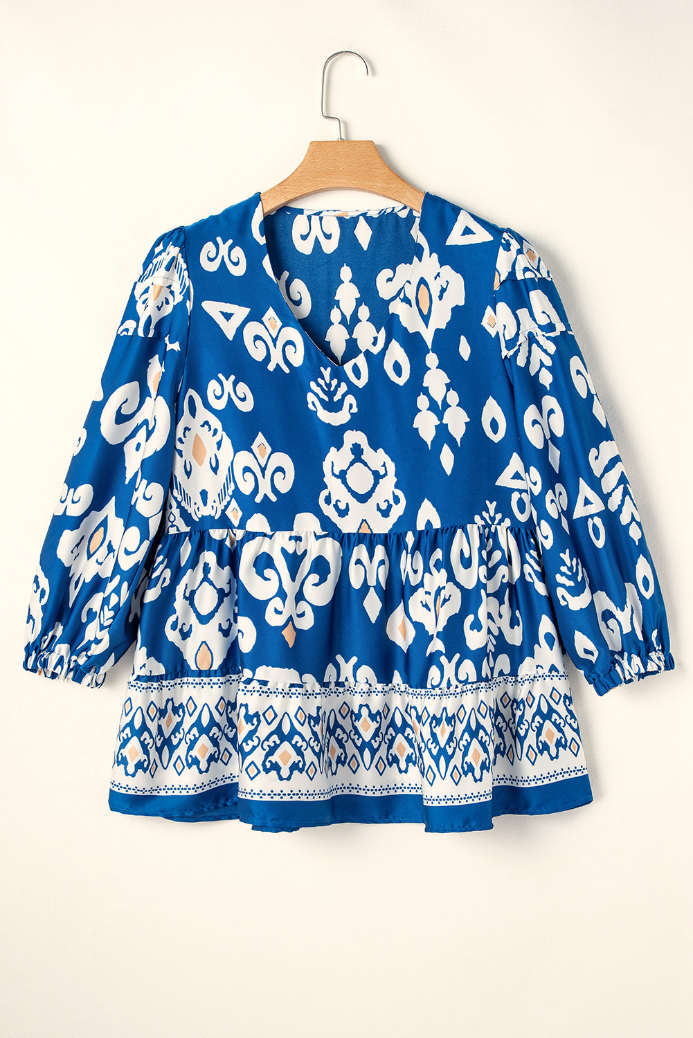 Boho chic V-neck blouse in vibrant cobalt blue with white and peach patterns, featuring a tiered design.