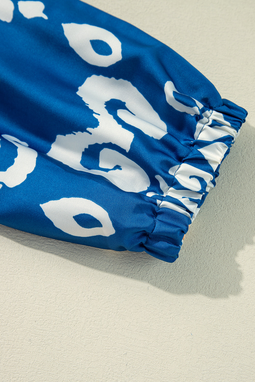 Close-up of cobalt blue blouse sleeve with white boho print and elastic gather, showcasing relaxed chic style.