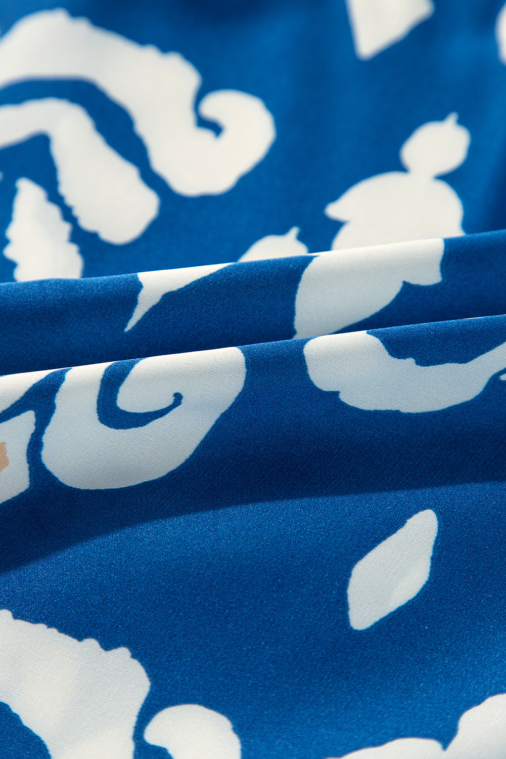 Close-up of cobalt blue fabric featuring white and peach boho patterns, showcasing elegance and style.