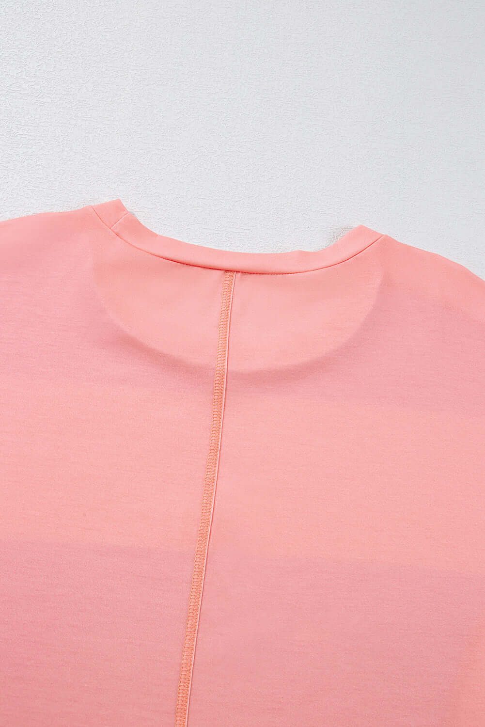 Pink crew neck top detailing with seam and soft fabric texture.