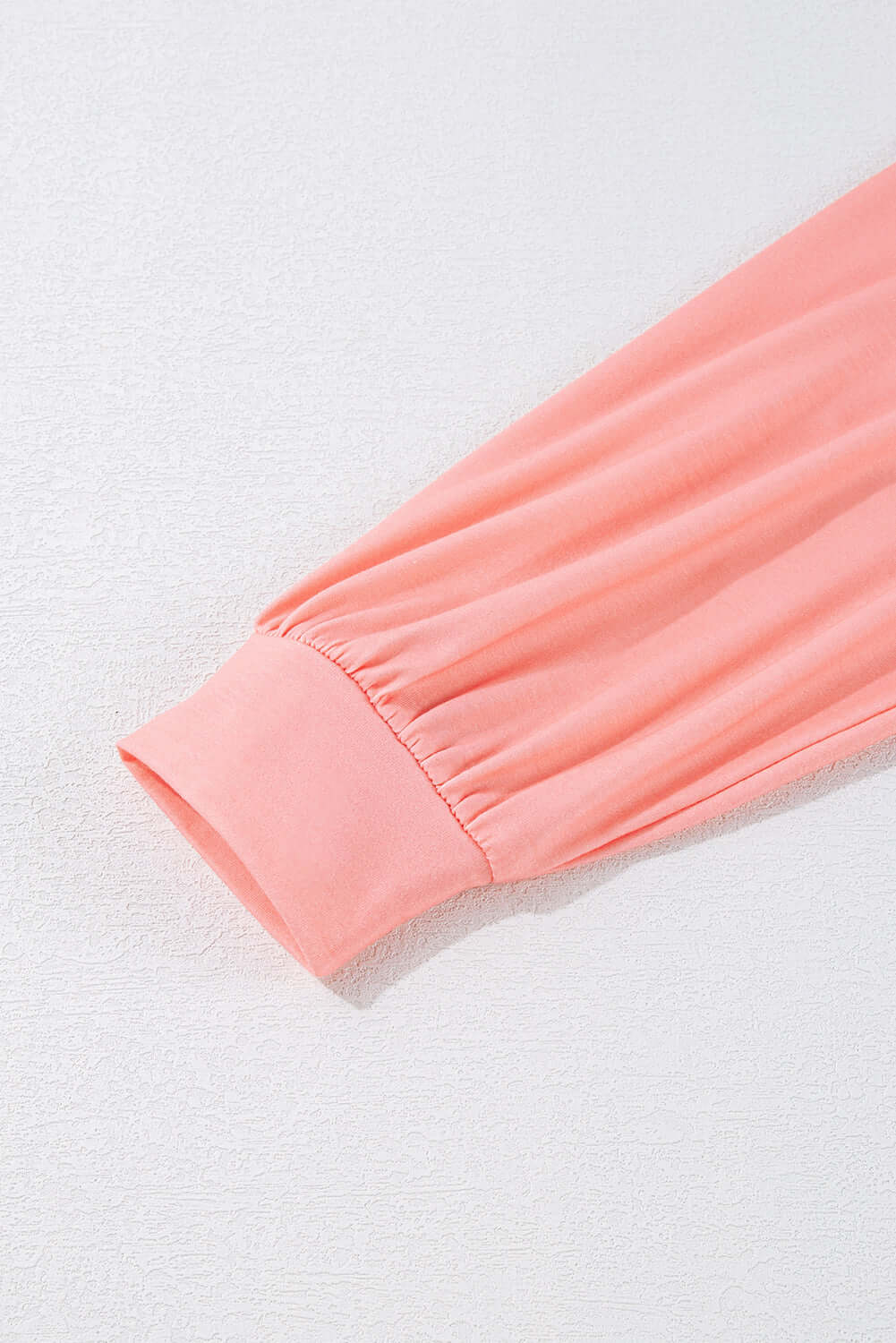 Close-up of pink sleeve with gathered cuff on vibrant color block crew neck top, perfect for layering and adding style.