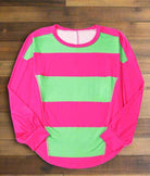 Pink and green colorblock crew neck top with striped pattern and drop shoulder design on wooden background.