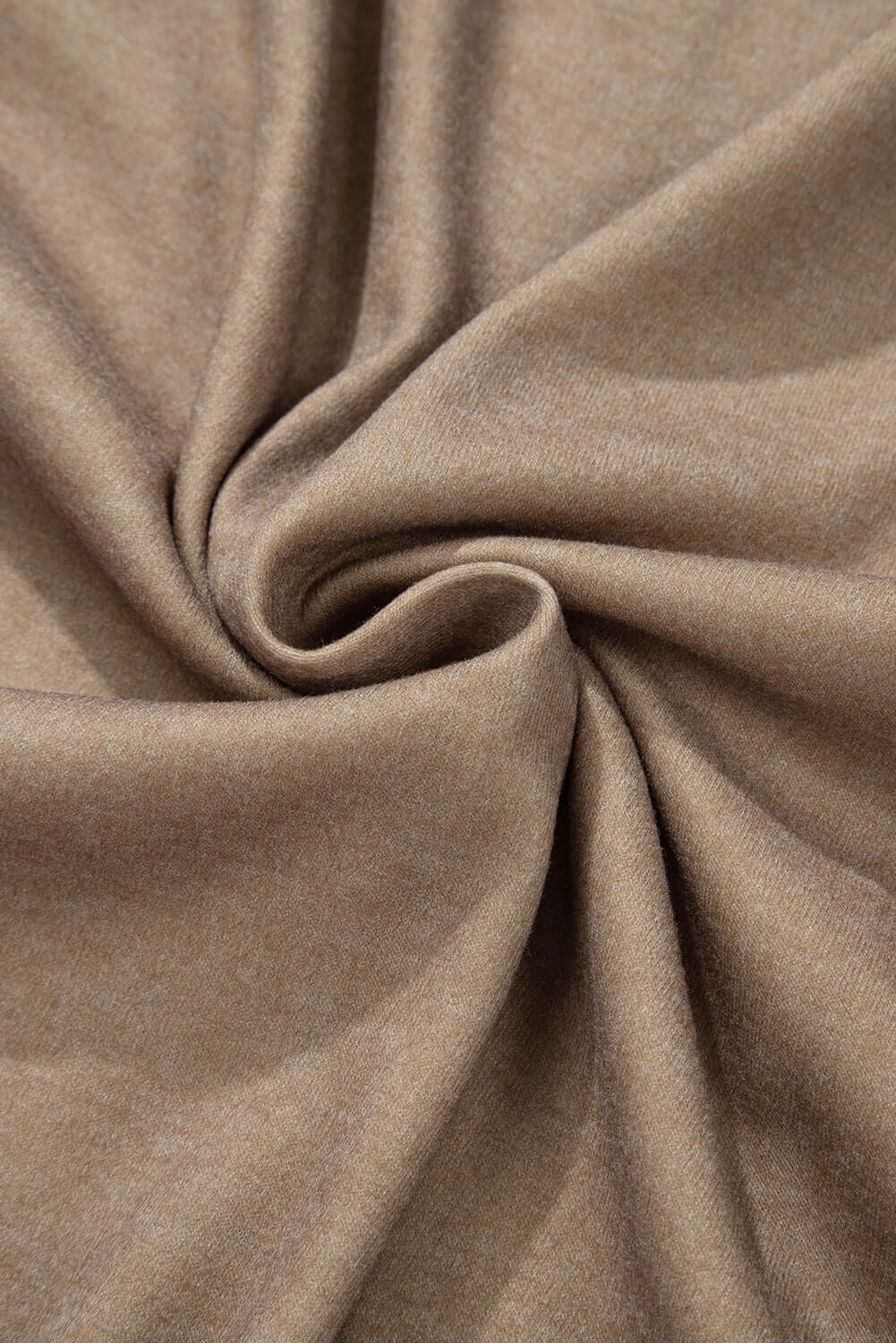 Close-up of swirling beige fabric texture showcasing soft polyester material for fashion apparel.