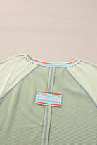 Stylish waffle knit t-shirt with raglan sleeves, patchwork design, and contrasting stripe detail on beige background.