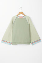 Stylish green T-shirt with wide bracelet sleeves, contrast stripe stitching, and raw hem finish on a hanger.