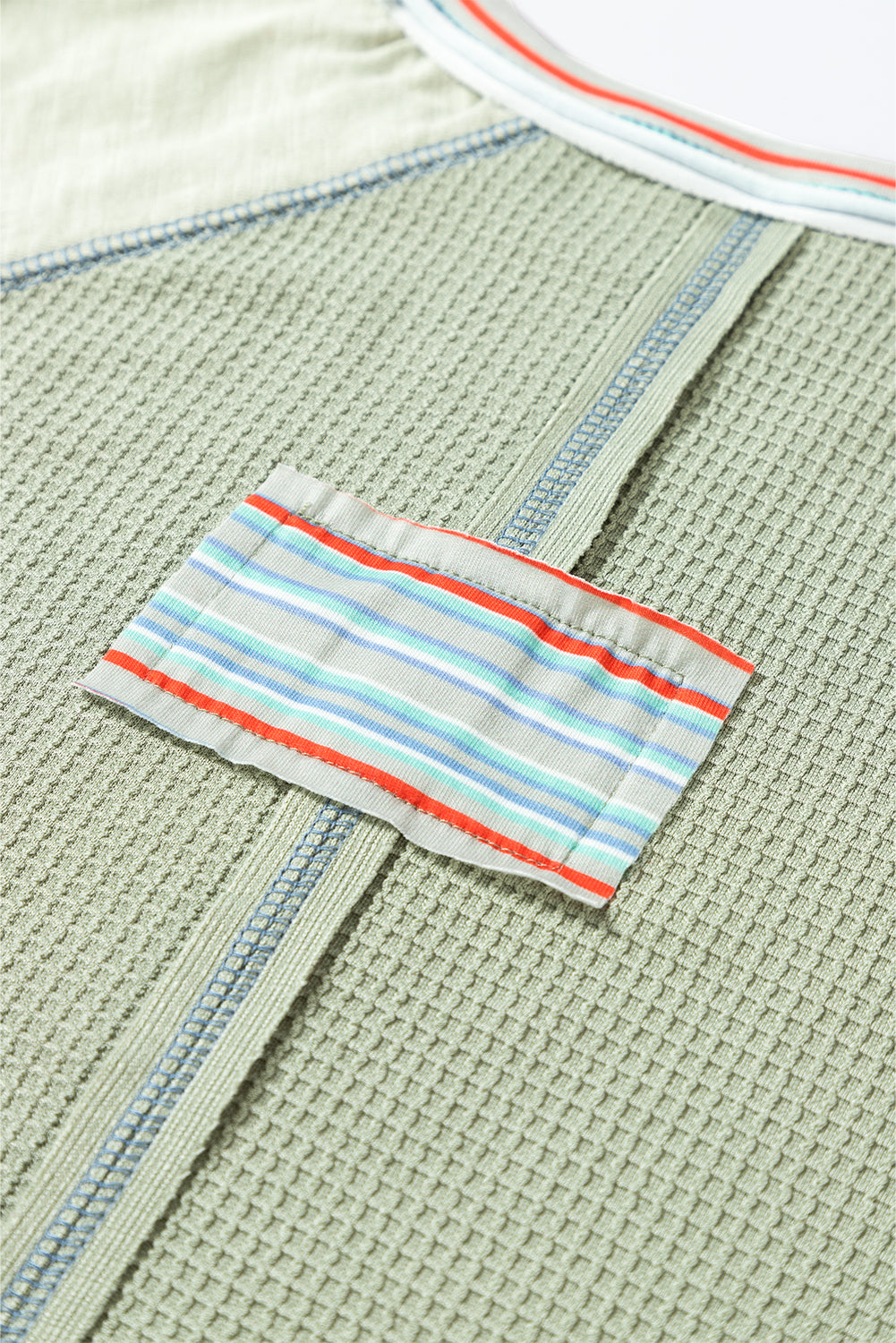 Waffle knit fabric with colorful patchwork and contrast stripe stitching detail on a stylish t-shirt design.