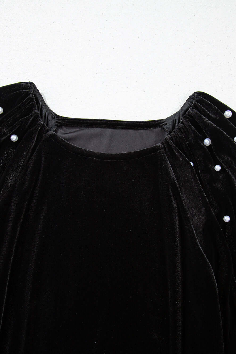 Elegant black velvet top with half puff sleeves and pearl bead embellishments, perfect for special occasions.