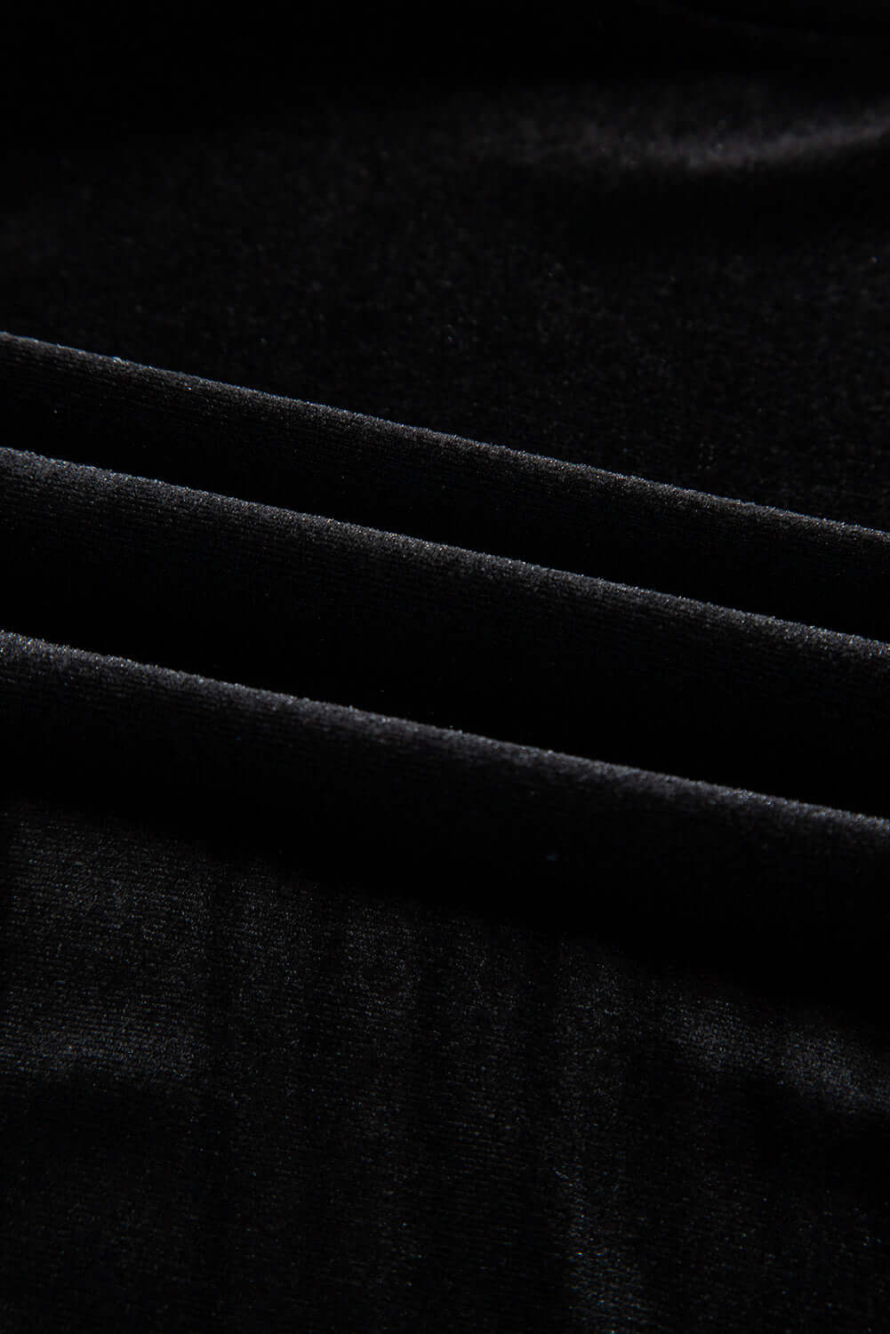 Close-up of luxurious black velvet fabric, showcasing soft texture and rich appearance perfect for elegant apparel.