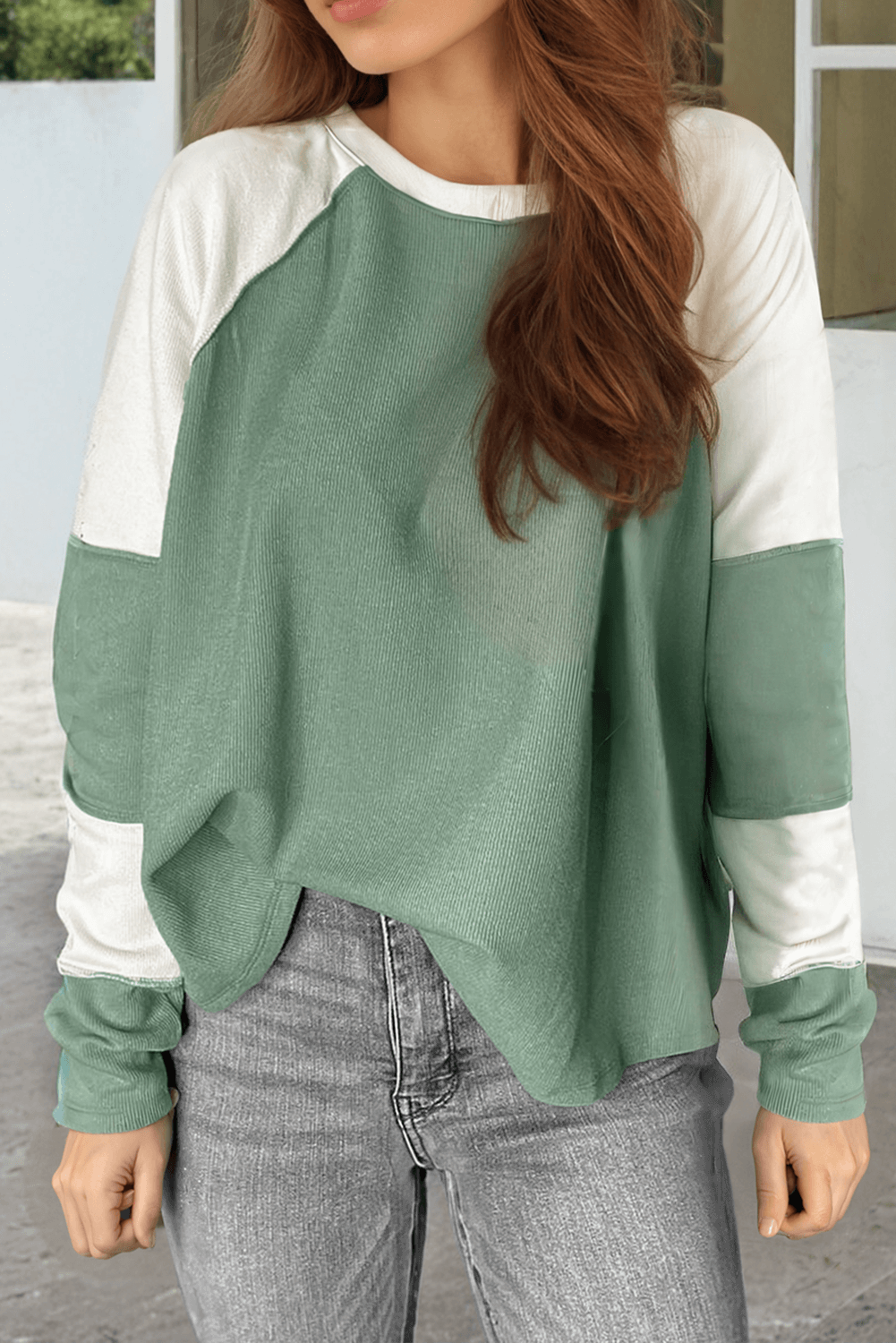 Woman wearing a stylish Whispering Willow top with a green color block design and cozy crew neck style.